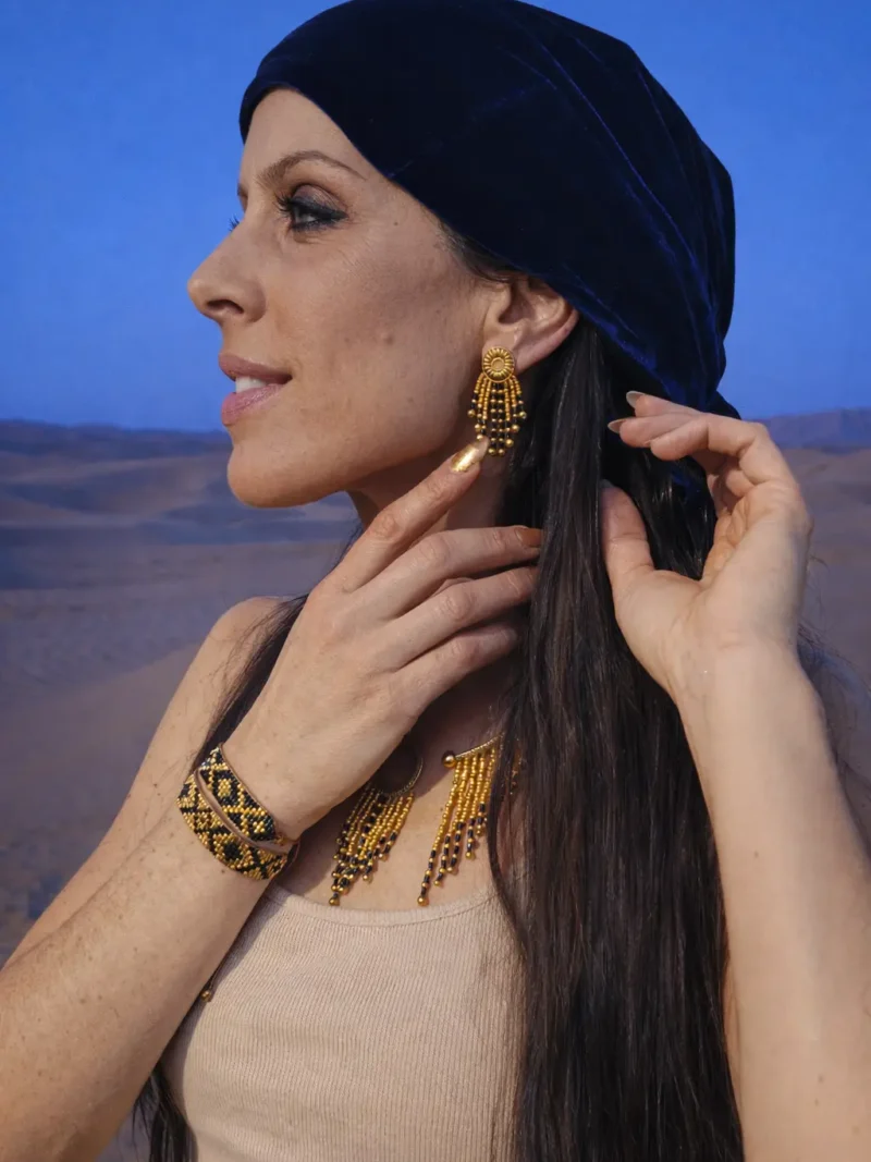 Petites boucles d’oreilles Amaziga Sacra portées avec bracelet et collier dans un environnement désertique
