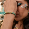 Bracelet Mira Calypsa porté au poignet avec robe bleue et bijoux coordonnés dans un décor naturel lumineux