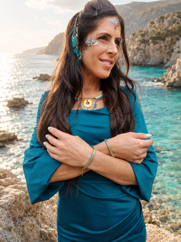 Bracelet Mira Calypsa porté au poignet dans une crique lumineuse, bijou artisanal Valdyria en perles Miyuki turquoise et dorées