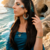 Boucles d’oreilles pendantes Mira Calypsa portées dans un décor rocheux naturel avec collier et bracelet assortis