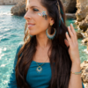 Boucles d’oreilles pendantes Mira Calypsa portées de profil avec cheveux ornés et ambiance naturelle lumineuse