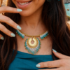 Collier majestueux Mira Calypsa en détail porté sur robe bleue avec design turquoise et or clair Valdyria