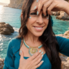 Collier majestueux Mira Calypsa porté près du visage avec main sur le cœur et ambiance naturelle lumineuse