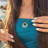 Collier à pendentif Mira Calypsa et artisanat précieux Collier à pendentif Mira Calypsa en détail porté sur robe bleue avec perles turquoise et dorées