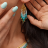 Boucles d’oreilles mini Mira Calypsa en gros plan avec perles Miyuki turquoise et dorées sur peau
