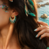Petites boucles d’oreilles Mira Calypsa et appel du large Petites boucles d’oreilles Mira Calypsa portées avec cheveux ornés et paysage marin en arrière plan