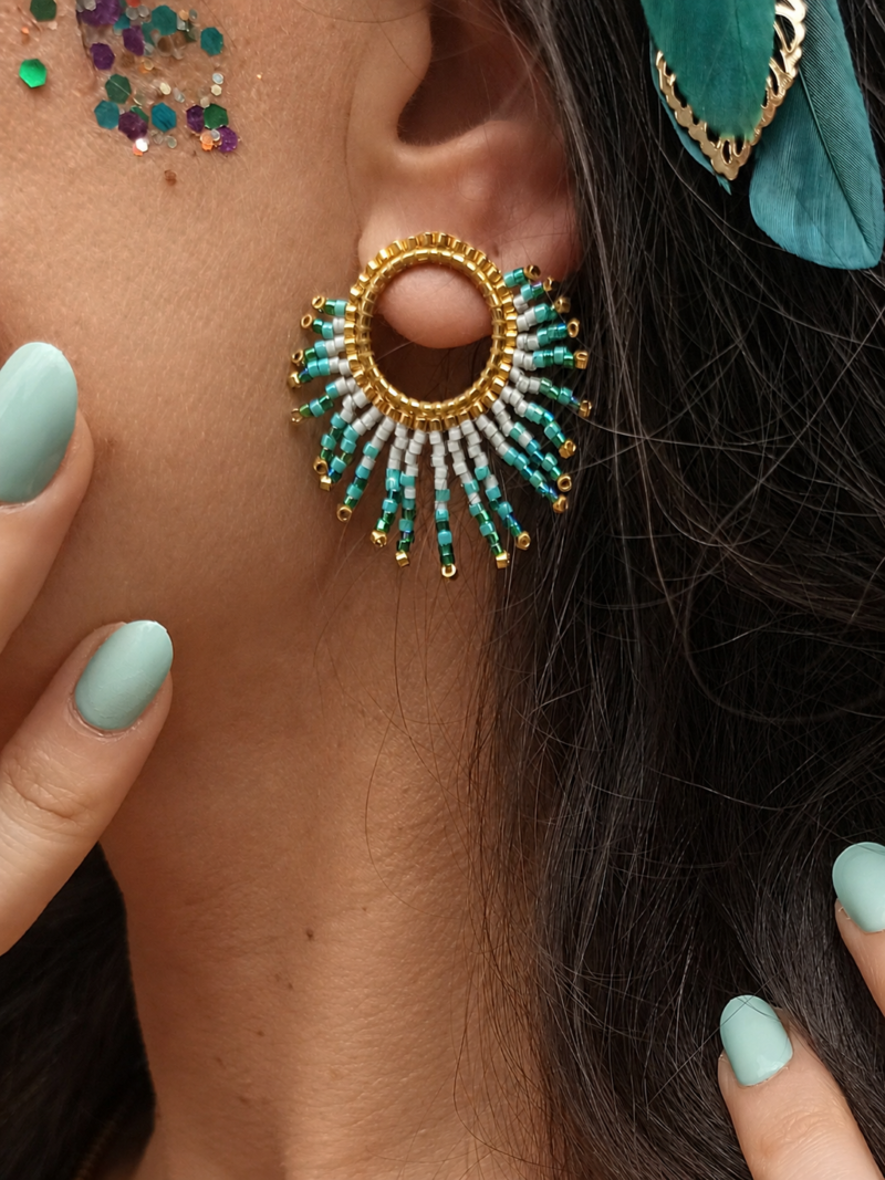 Petites boucles d’oreilles Mira Calypsa en détail porté avec perles turquoise et forme solaire marine