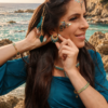 Petites boucles d’oreilles Mira Calypsa et talisman marin Petites boucles d’oreilles Mira Calypsa portées en profil près des rochers et de la mer Méditerranée
