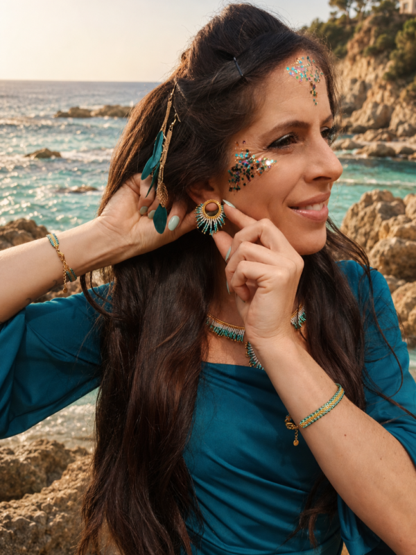 Petites boucles d’oreilles Mira Calypsa et talisman marin Petites boucles d’oreilles Mira Calypsa portées en profil près des rochers et de la mer Méditerranée
