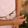 Bracelet Mira Aurora et talisman d’aube Bracelet Mira Aurora porté en détail sur le poignet avec robe rose pâle et décor floral ancien, bijou fait main Valdyria