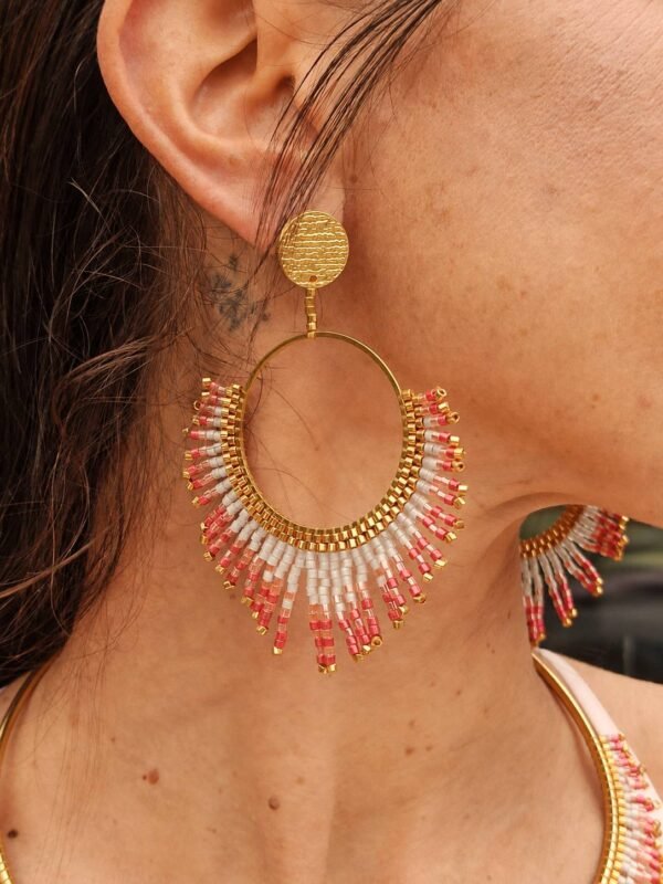 Boucles d’oreilles pendantes Mira Aurora portées en gros plan, bijou artisanal Valdyria en perles Miyuki rose aurore, corail doux et or pâle