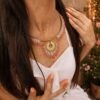 Collier majestueux Mira Aurora et lumière du recommencement Collier majestueux Mira Aurora porté en gros plan sur robe blanche et rose pâle, bijou artisanal Valdyria en perles Miyuki dans une ambiance d’aube florale