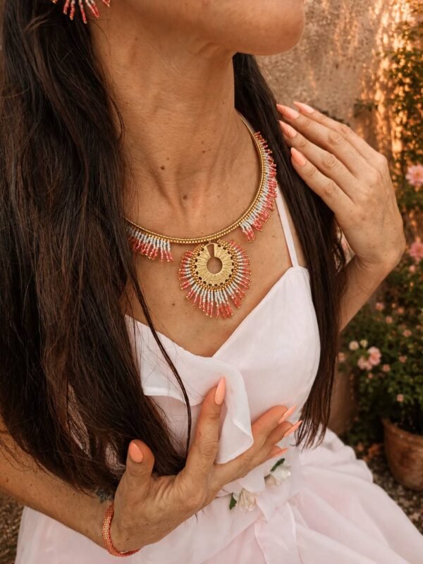 Collier majestueux Mira Aurora et lumière du recommencement Collier majestueux Mira Aurora porté en gros plan sur robe blanche et rose pâle, bijou artisanal Valdyria en perles Miyuki dans une ambiance d’aube florale