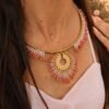 Collier majestueux Mira Aurora et bijou avec âme Collier majestueux Mira Aurora porté en détail avec main sur le buste, bijou fait main Valdyria aux tons rose, corail et or pâle