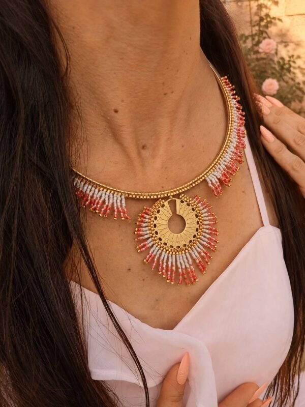 Collier majestueux Mira Aurora et bijou avec âme Collier majestueux Mira Aurora porté en détail avec main sur le buste, bijou fait main Valdyria aux tons rose, corail et or pâle