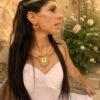 Collier majestueux Mira Aurora et élégance du matin Collier majestueux Mira Aurora porté avec robe claire dans un jardin ancien fleuri, bijou artisanal Valdyria inspiré de l’aube