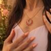 Collier à pendentif Mira Aurora et bijou avec âme Collier à pendentif Mira Aurora porté en détail avec main sur le décolleté, bijou fait main Valdyria en perles Miyuki roses et dorées
