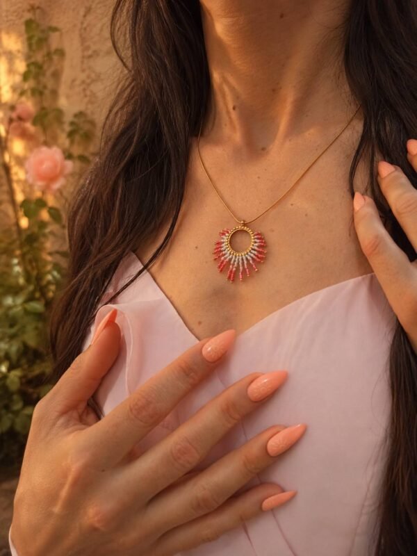 Collier à pendentif Mira Aurora et bijou avec âme Collier à pendentif Mira Aurora porté en détail avec main sur le décolleté, bijou fait main Valdyria en perles Miyuki roses et dorées