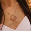 Collier à pendentif Mira Aurora et renaissance douce Collier à pendentif Mira Aurora porté sur robe claire en gros plan, bijou artisanal inspiré de l’aube et du renouveau