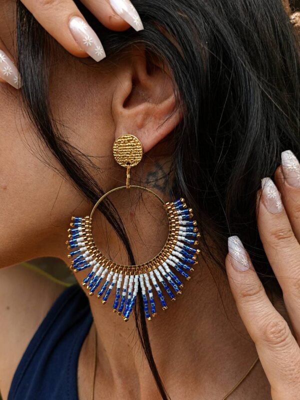 Boucles d’oreilles pendantes Mira Obscura et mystère nocturne Boucles d’oreilles pendantes Mira Obscura portées dans un décor minéral, bijou femme bleu nuit et or au style artisanal Valdyria