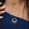 Collier à pendentif Mira Obscura et mystère crépusculaire Collier à pendentif Mira Obscura porté avec tenue bleu nuit dans un décor rocheux, bijou artisanal femme Valdyria