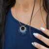 Collier à pendentif Mira Obscura et artisanat français Collier à pendentif Mira Obscura porté de profil avec tenue asymétrique bleu marine, création artisanale française