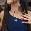 Collier à pendentif Mira Obscura et création en petite série Collier à pendentif Mira Obscura porté debout avec tenue bleu nuit et paysage minéral, bijou en petite série