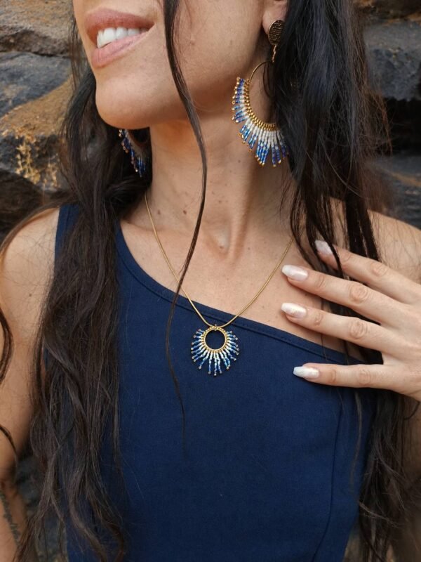 Collier à pendentif Mira Obscura et création en petite série Collier à pendentif Mira Obscura porté debout avec tenue bleu nuit et paysage minéral, bijou en petite série