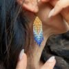 Mini boucles d’oreilles Mira Obscura portées près de l’oreille avec franges bleues et dorées, bijou fait main en Alsace