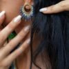 Petites boucles d’oreilles Mira Obscura portées avec collier assorti sur fond rocheux, bijou femme bleu nuit et or