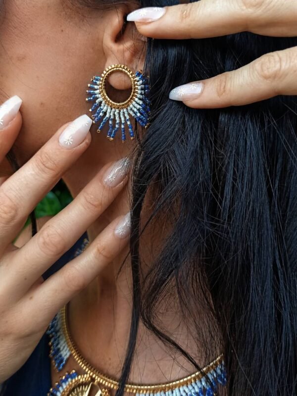 Petites boucles d’oreilles Mira Obscura portées avec collier assorti sur fond rocheux, bijou femme bleu nuit et or