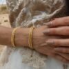 Bracelet Mira Helia porté au poignet en extérieur, bijou talisman Valdyria en perles Miyuki dorées et nuances or miel