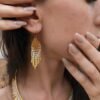 Mini boucles d’oreilles Mira Helia portées en gros plan, bijou artisanal Valdyria en perles Miyuki dorées et ambrées
