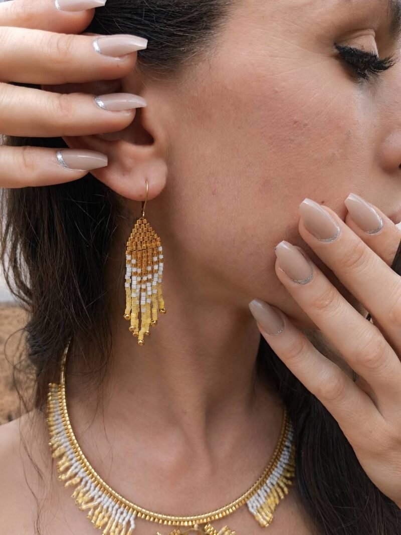 Mini boucles d’oreilles Mira Helia portées en gros plan, bijou artisanal Valdyria en perles Miyuki dorées et ambrées
