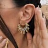 Petites boucles d’oreilles Mira Helia portées près du visage avec détails dorés, bijou fait main inspiré par la résilience