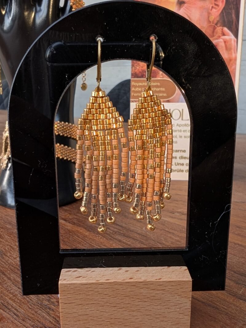 Mini boucles d’oreilles Apollisia Solaris et bijou talisman Ces mini boucles d’oreilles Apollisia Solaris mettent en valeur l’artisanat français cher à Valdyria. Leur construction délicate en perles Miyuki souligne le temps du geste, la précision et l’attention portée aux détails. Inspirées par la royauté solaire et les ornements anciens, elles apportent une touche lumineuse au visage sans perdre leur finesse. Une création faite main pour celles qui recherchent un bijou raffiné, durable et porteur d’une vraie présence symbolique.
