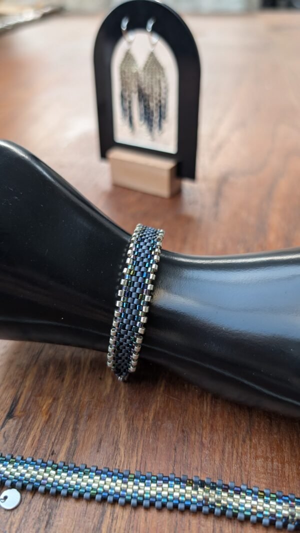Bracelet Artemesia Lunaris foncé présenté sur support noir, bijou artisanal français tissé en perles Miyuki aux reflets nocturnes