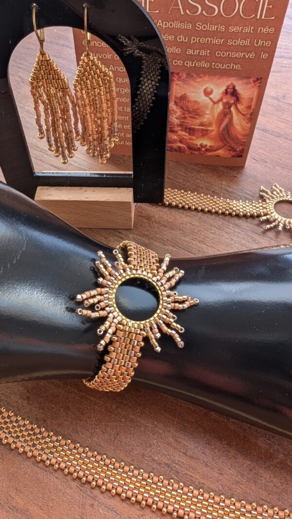 Bracelet motif Apollisia Solaris et artisanat français Bracelet motif Apollisia Solaris présenté sur support noir, bijou artisanal français doré à inspiration solaire