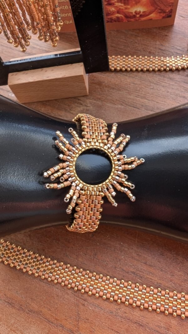 Bracelet motif Apollisia Solaris et talisman solaire Bracelet motif Apollisia Solaris en gros plan, bijou talisman Valdyria doré inspiré du soleil et de la royauté solaire
