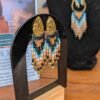 Les petites boucles d’oreilles Nilyra Maria puisent leur identité dans une palette minérale, entre turquoise profond, sable clair et bronze chaud. Ces nuances donnent au bijou une sensation organique, presque terrestre, tout en conservant la précision graphique des perles Miyuki. Fabriquée artisanalement en France, cette pièce Valdyria célèbre la nature, le travail manuel et les créations qui possèdent une véritable présence. Un bijou féminin à la fois sensible, graphique et intemporel.