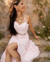 Collier majestueux Mira Aurora porté assis dans un jardin ancien avec robe claire, bijou artisanal féminin au style Valdyria
