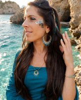 Boucles d’oreilles pendantes Mira Calypsa portées de profil avec cheveux ornés et ambiance naturelle lumineuse