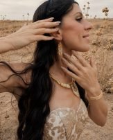 Mini boucles d’oreilles Mira Helia portées avec parure dorée, bijou éthique femme aux reflets chauds et solaires